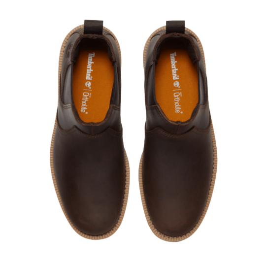 Pair of brown leather shoes with orange soles on a white background