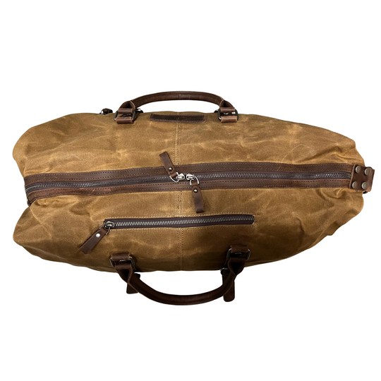 Brown waxed canvas duffel bag with leather straps on a white background