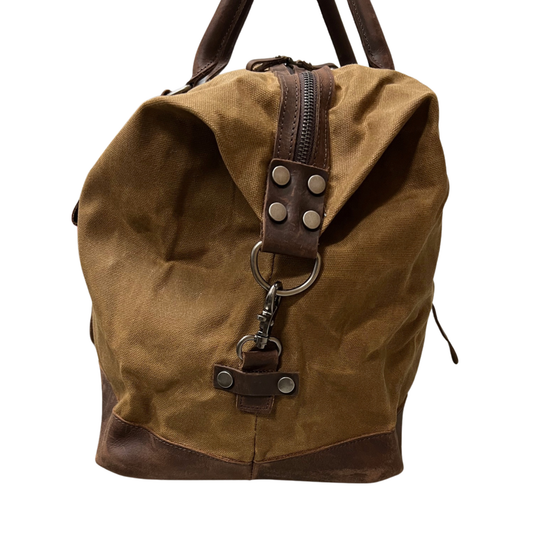 Brown waxed canvas backpack with leather accents on a white background
