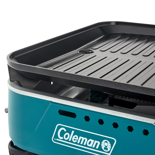 Teal tabletop grill with a black ridged griddle plate and Coleman logo