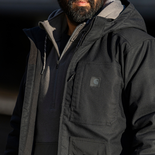 Black hooded work jacket with large chest pockets and a small Carhartt patch