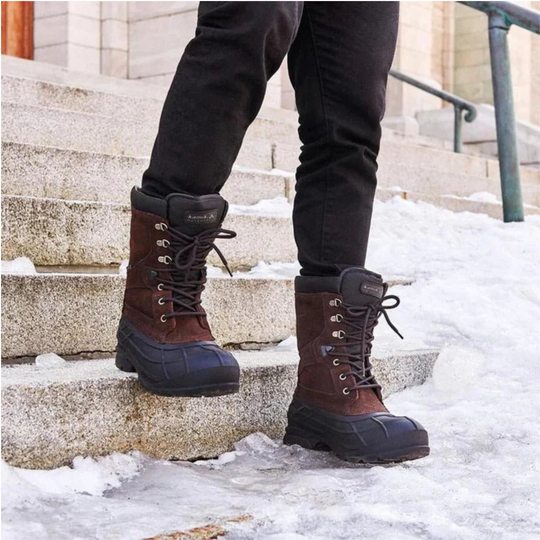 Brown winter boots with black soles on a snowy step