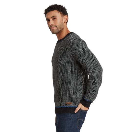 A man wearing a dark gray textured knit sweater with black ribbed trim, paired with blue jeans, shown from a side profile against a plain white background.