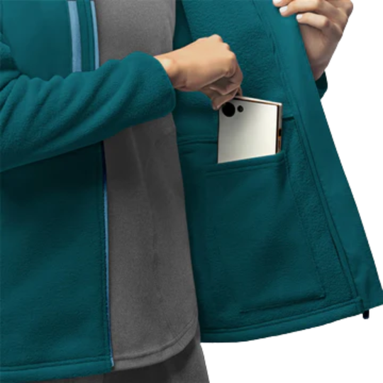 Person wearing a teal jacket with a pocket holding a phone on a white background