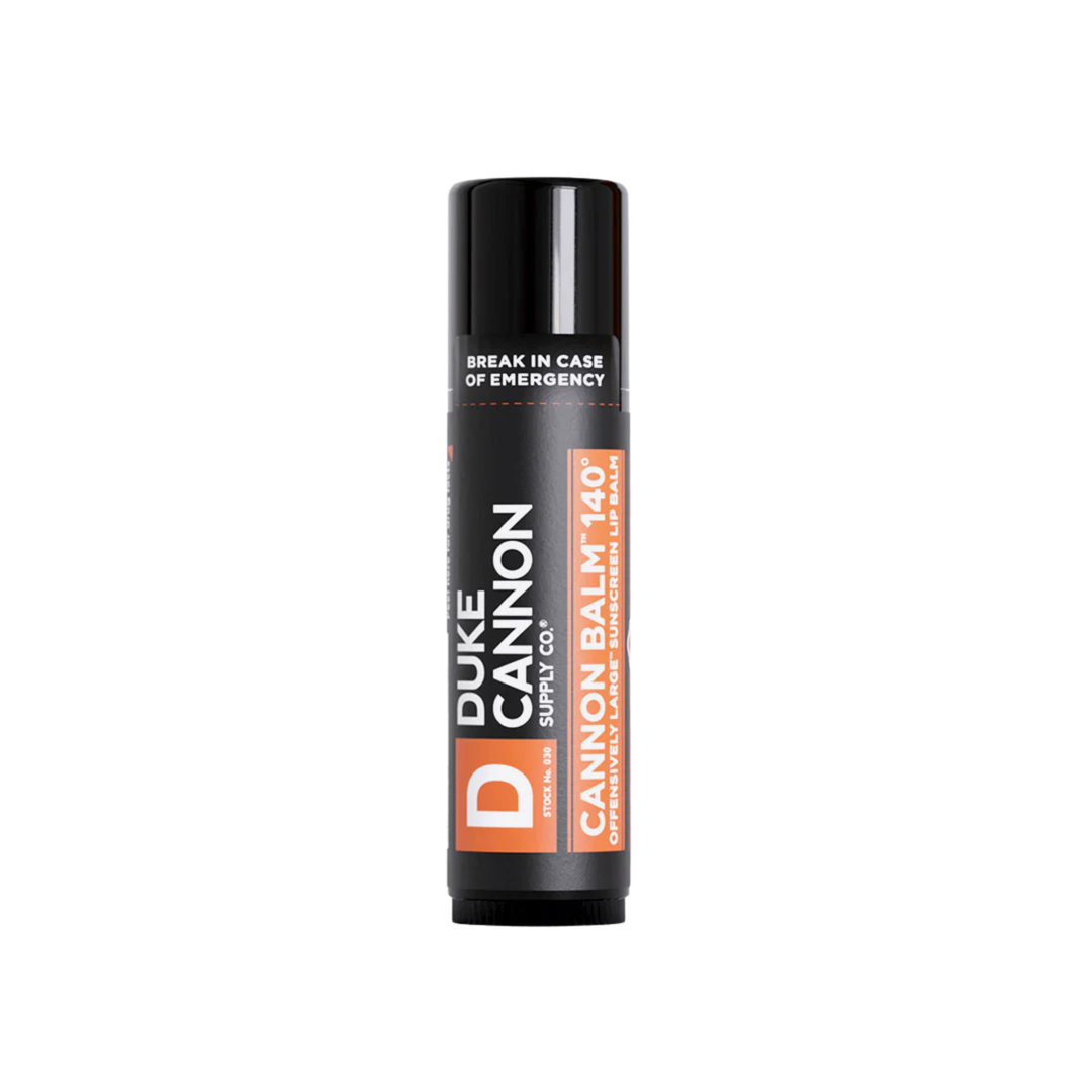 Black lip balm tube with orange labels and visible text “BREAK IN CASE OF EMERGENCY”
