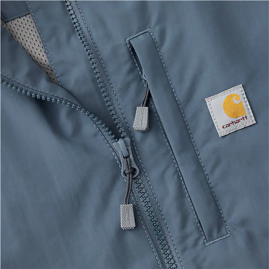Close-up of a blue-gray Carhartt jacket with zipper pockets and a logo patch