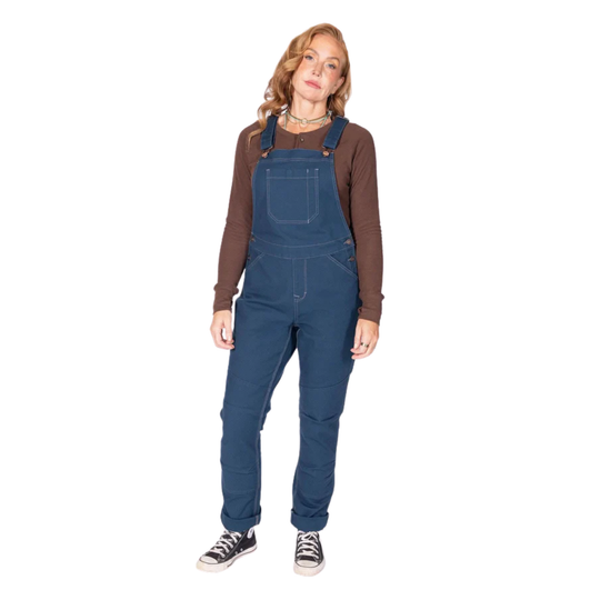 Blue women’s overalls worn over a brown long-sleeve shirt, with front pocket and cuffed legs