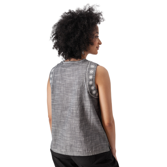 Woman wearing a sleeveless patterned top against a white background