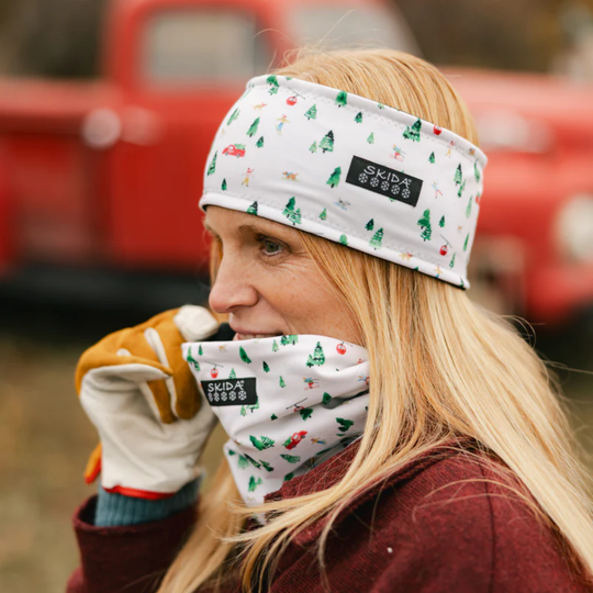 Person wearing a headband and gloves with a visible brand logo, standing in front of a red vehicle.