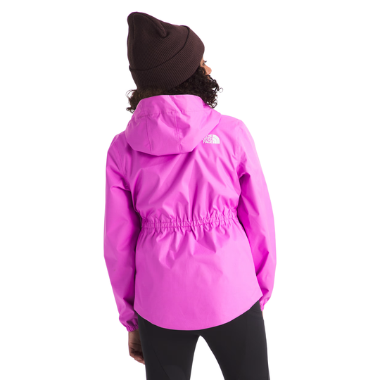 A person shown from the back wearing a bright pink hooded jacket with a drawstring waist, black leggings, and a dark brown beanie against a plain white background. The small white The North Face logo is visible on the upper back of the jacket.