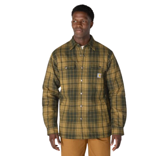 A man wearing a Carhartt long-sleeve plaid button-up shirt in olive green and tan, paired with tan pants, against a plain white background.
