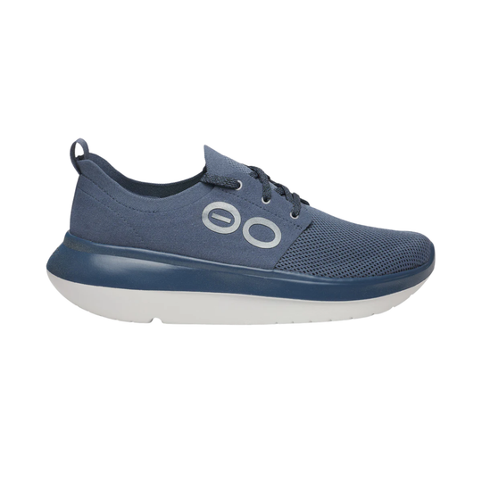 A single blue slip-on sneaker with a thick white sole, featuring a textured mesh upper and a prominent circular logo on the side.