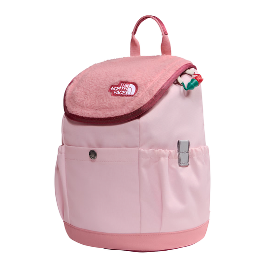 A light pink The North Face backpack with a plush pink flap, featuring a front pocket with a snap button, a side pocket with a silver zipper pull, and a small colorful hanging charm, shown on a plain white background.