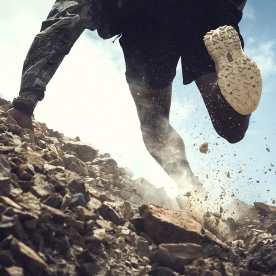 Rocky background with the bottom shoe sole showing. Rocks kicked up in the air.