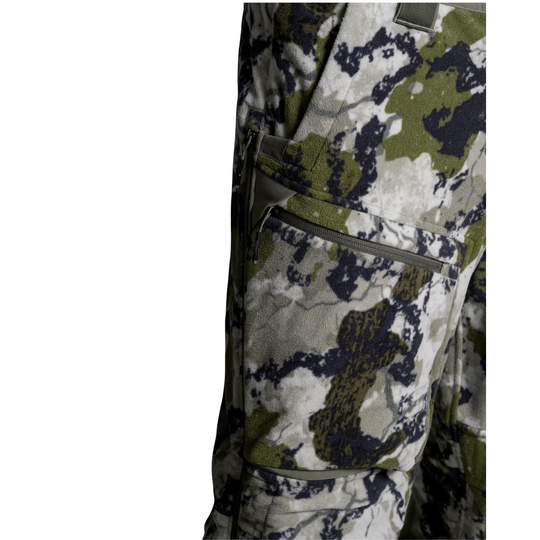 Close-up of camouflage pants showing a side cargo pocket with a zipper and a digital camo pattern in green, gray, and black.
