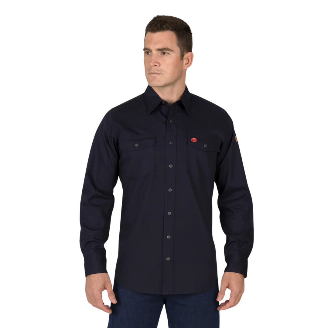 A man wearing a dark navy long-sleeve button-up shirt with two chest pockets and a small red logo on the left chest, paired with dark blue jeans, against a plain white background.