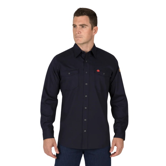 A man wearing a dark navy long-sleeve button-up shirt with two chest pockets and a small red logo on the left chest, paired with dark blue jeans, against a plain white background.