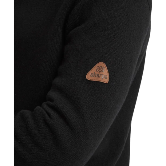 A man wearing a black ribbed mock neck quarter-zip sweater with a brown zipper pull. With a Sherpa patch on the sleeve. Shown from a side profile against a white background.