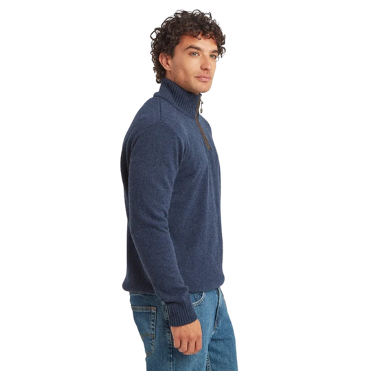 A man wearing a navy blue quarter-zip mock neck sweater and blue jeans, shown in profile against a solid white background.