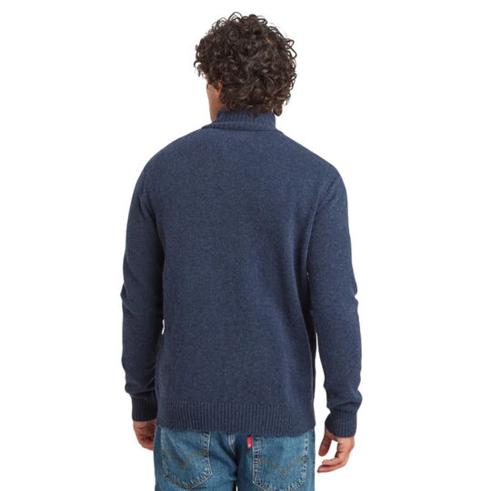 A man viewed from behind wearing a navy blue knit sweater and blue jeans against a plain white background.