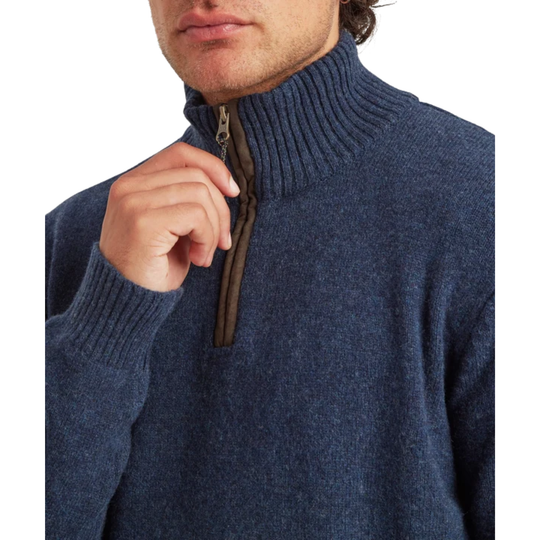 Close-up of a man wearing a navy blue ribbed knit quarter-zip sweater, pulling the zipper with his hand against a white background.