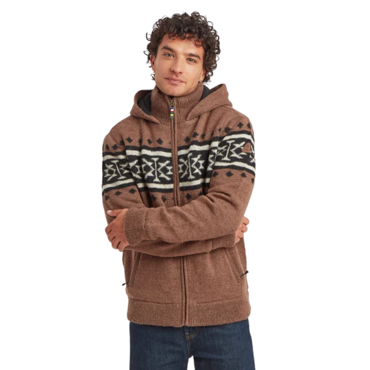 A man wearing a brown zip-up hoodie with a black and white geometric pattern across the chest and shoulders, paired with blue jeans, against a plain white background.