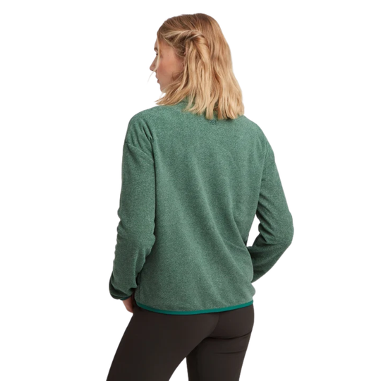 A woman with blonde hair tied back, viewed from behind, wearing a heathered green long-sleeve fleece pullover and dark leggings against a plain white background.