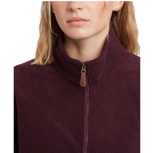 Close-up of a woman wearing a dark burgundy fleece zip-up vest with a high collar and a brown leather zipper pull, shown against a plain white background.