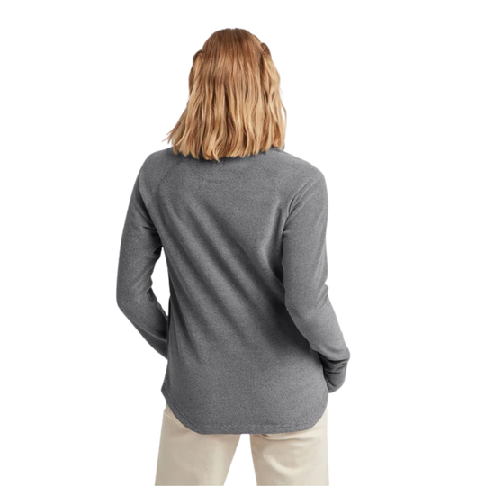 A woman viewed from the back wearing a heather gray long-sleeve top and light beige pants against a plain white background.