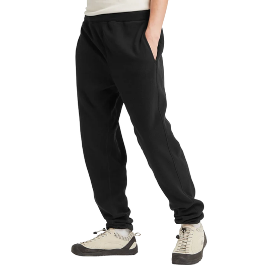 Black sweatpants shown on a model from the waist down, paired with off-white sneakers, against a plain white background.