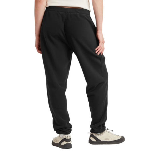 A person shown from the back wearing black jogger sweatpants and light beige athletic shoes against a plain white studio background.