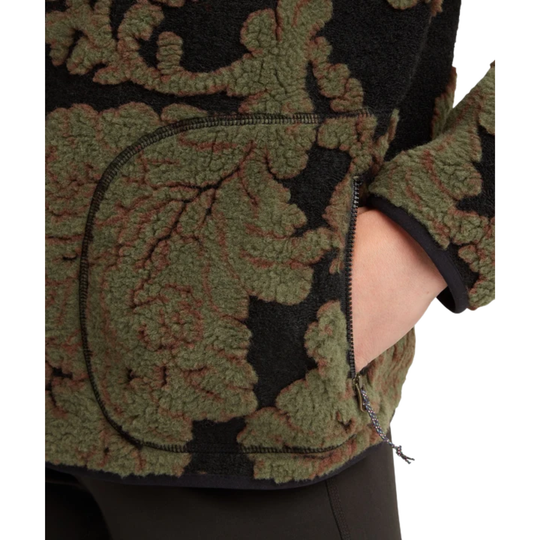 Close-up of a fleece jacket with a textured green and black damask pattern, featuring a side pocket with a hand inside, on a white background.