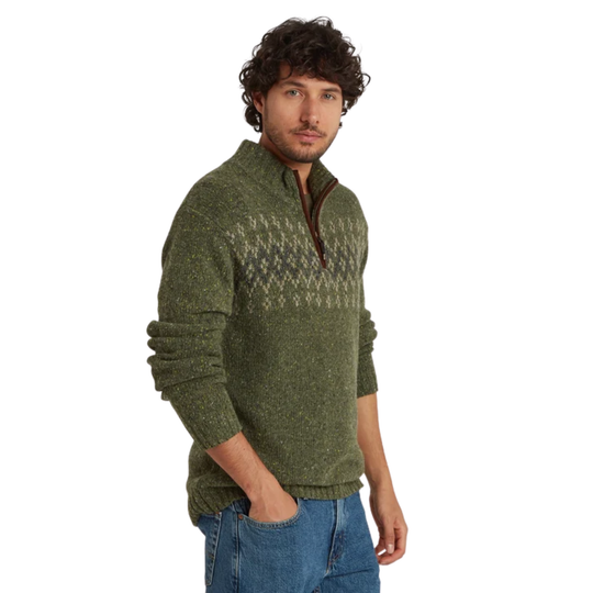 A man wearing a green knit quarter-zip sweater with a brown zipper and a beige geometric pattern across the chest, paired with blue jeans, set against a plain white background.