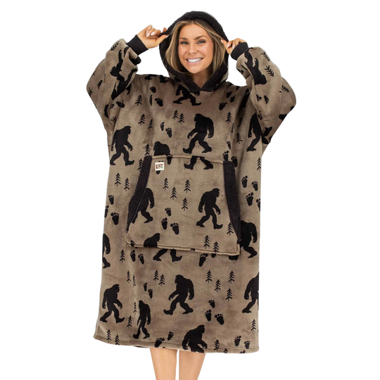 A woman wearing a brown hooded lounge robe with a black Bigfoot and tree print, shown against a plain white background.