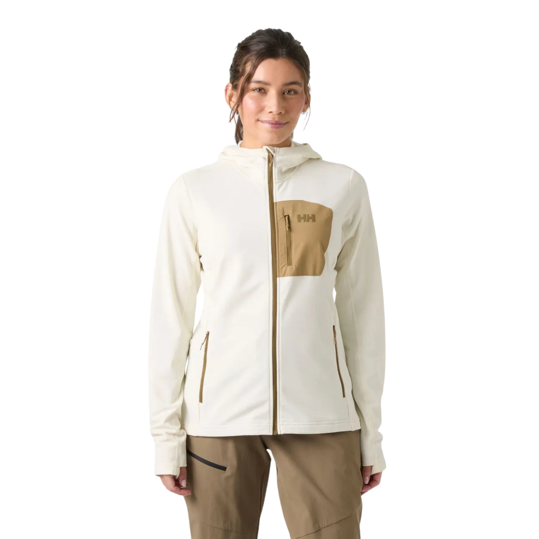 A woman modeling a hooded zip-up jacket in off-white with a tan chest pocket and matching tan pants, photographed against a plain white studio background.
