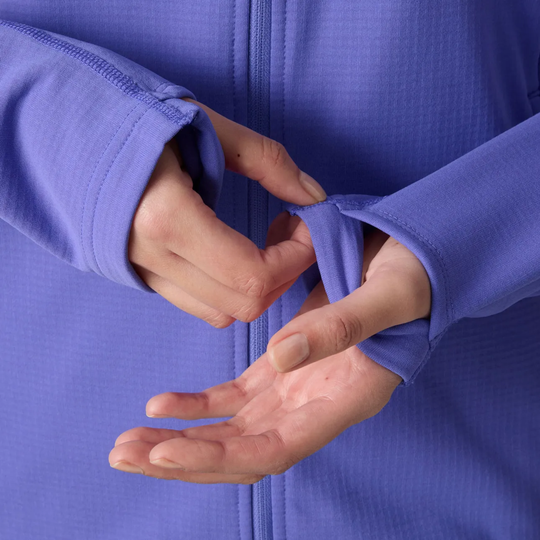 Close-up of a person's hands adjusting the cuff of a textured periwinkle blue zip-up jacket.