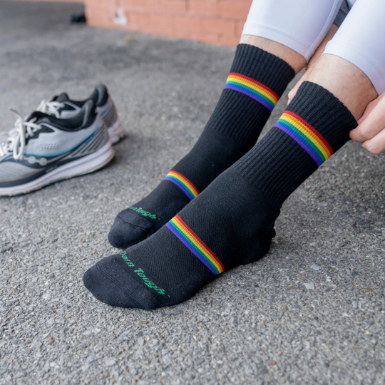 Darn Tough Vermont Men's Prism Micro Crew Lightweight Running Sock - Black on black pavement. A pair of Saucony running shoes in the background. 