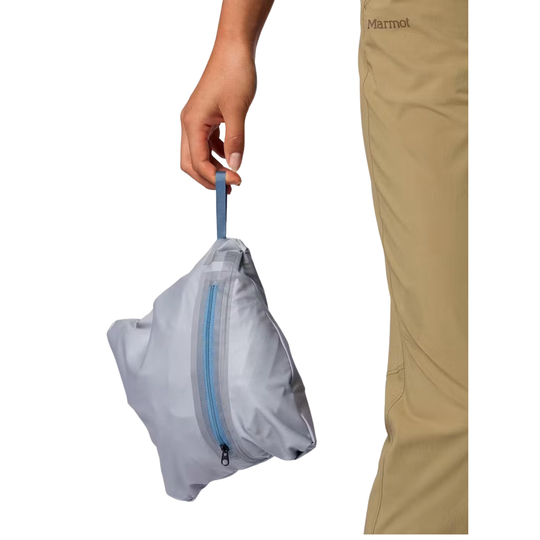 A hand holding a light gray Marmot waterproof stuff sack with a blue zipper, shown next to a cropped view of tan Marmot pants on a white background.