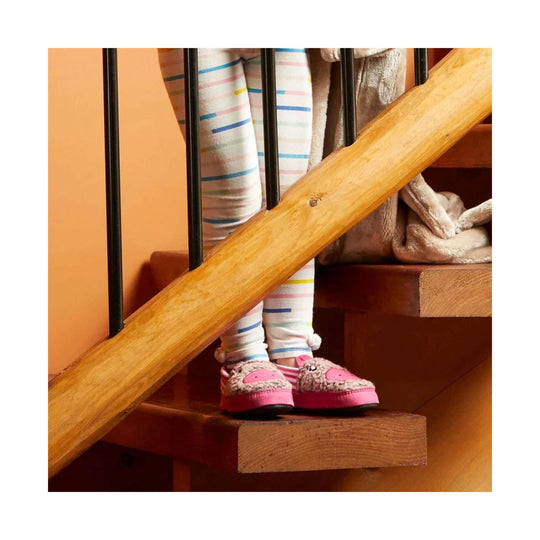 Pink fuzzy cat-face moc slippers on a child standing on wooden stairs