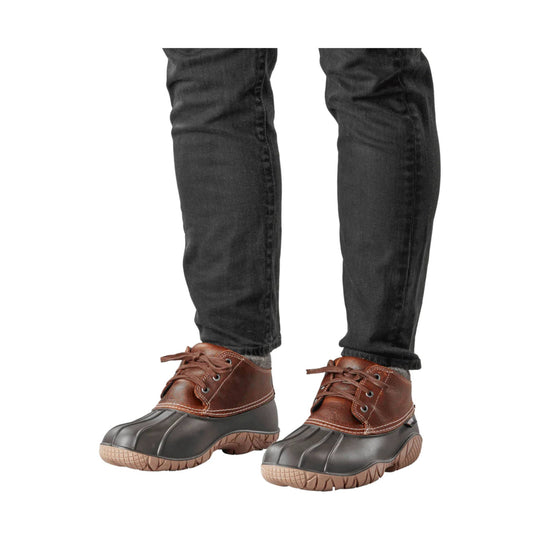 Brown lace-up insulated boots with black rubber toe and sole, shown on a model wearing black pants