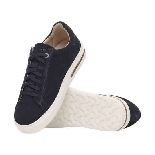 Navy suede low-top sneaker with white sole and laces, shown from the side and sole