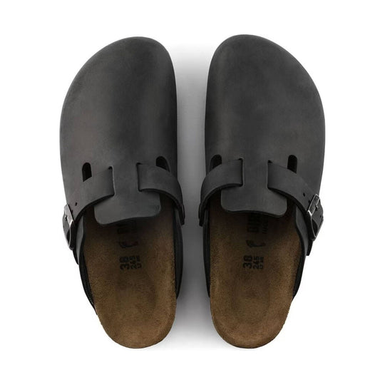 Pair of black clogs with rounded toes, buckled straps, and cork footbeds, viewed from above