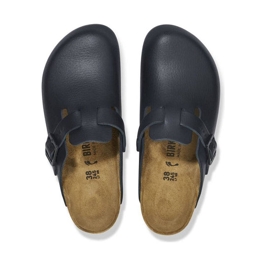 Pair of black leather clogs with tan suede insoles and buckle straps, top view