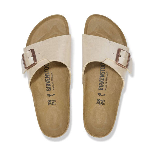 Pair of cream slip-on sandals with wide buckled straps and contoured cork footbeds