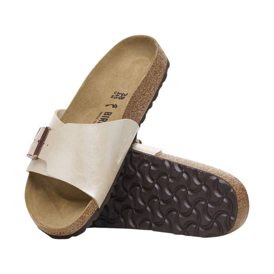 Cream leather slide sandal with adjustable buckle strap and cork footbed, shown with a dark treaded sole underneath