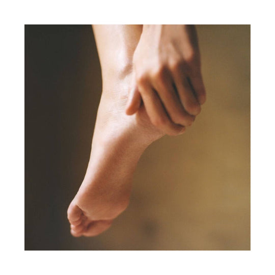Bare foot being held in a close-up, warm-toned lifestyle shot