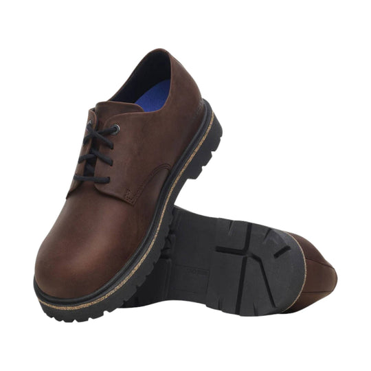 Brown leather lace-up shoe with black lug sole, shown from the side and bottom
