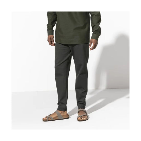 Two-strap stone and taupe sandal with cork footbed, shown on a model wearing dark pants