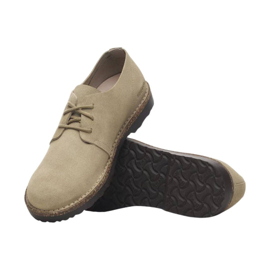 Pair of beige suede low-top lace-up shoes with dark treaded soles