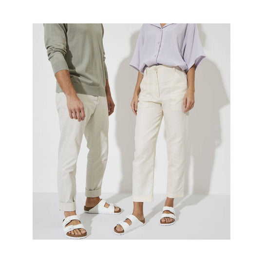 White double-strap sandals worn with light pants by two models